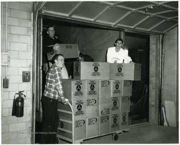 Men stock a fallout shelter with boxes of crackers.  'Probably inside the old WVU bookstore.'