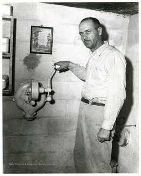 Man holding the handle of the air blower in the fallout shelter.