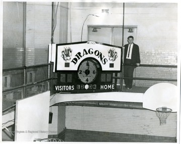 A gentleman is standing behind the Morgantown Junior High School Dragons Scoreboard.