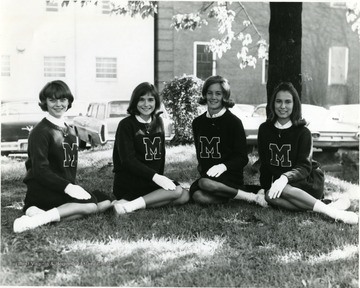 A photo of four Morgantown High cheerleaders. Two of the cheerleaders are Joyce Stonebreaker 'right' and Mary Kay Corum 'center right'.