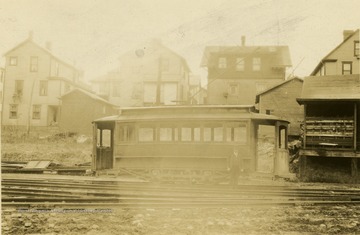 Man standing on the tracks next to a trolley in Morgantown. 'Photo found in city directory.'