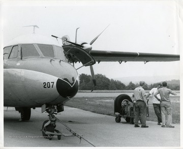 Three airport employees stand next to a Nord N262 airplane at the Morgantown Municipal Airport. 