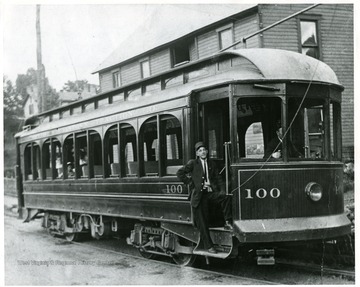 A conductor poses with his streetcar, South Morgantown Traction Car, Number 100, at the south end of University Avenue bridge in Morgantown, West Virginia.
