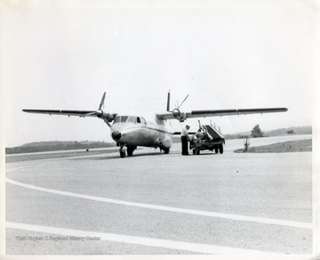 Unidentified men with a loading vehicle stopped next to a Nord N262 airplane.