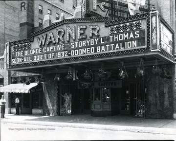 The front enterance of the Warner Theatre. The movie 'The Blonde Captive' is advertised on the marquee.