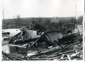 View of debris form a demolished home and a car after a wind storm.