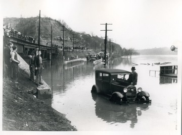 Man with his automobile in flood water along the Monongahela River on US 19 and West Virginia State Road 7, 100 near Morgantown, West Virginia.