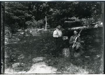 View of two successful hunters with squirrels and a groundhog resting on a stone in the woods in Morgantown, W. Va.
