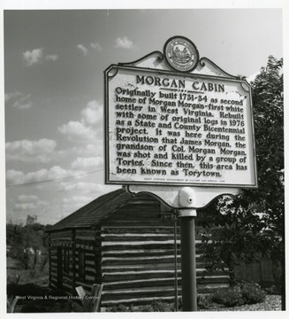 Historical marker reads 'Morgan Cabin, originally built 1731-34 as second home of Morgan Morgan, first white settler in West Virginia. Rebuilt with some of original logs in 1976 as a State and County Bicentennial project. it was here during the Revolution that James Morgan, the grandson of Col. Morgan Morgan, was shot and killed by a group Tories. Since then, this are has been known as Torytown.'
