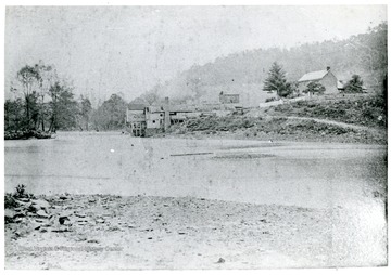 View of the Heckert Family Mill and Home at Troy, Gilmer County, W. Va. 'Original photo is very faded and owned by Clyde Moneypenny, age 93 in 1977, Clarksburg, W. Va.  1950 Flood took out Mill Dam.  The dam remained long after the mill had fallen down.'