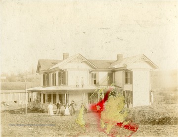 'Dwyer Home in Rader Valley'. Portrait of family standing along the front of their home. Two young girls pose for the picture while standing on the porch roof. 