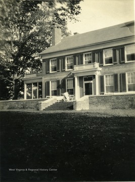 View of the Tuscawella Home in Lewisburg, West Virginia. A person sits outside on a bench reading a newspaper.