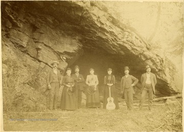 View of a small group of people standing by the Rock House in Petersburg, W. Va. 'Mrs. Annie Smith with guitar.'