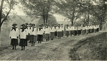 Girls in uniform walking down a road.