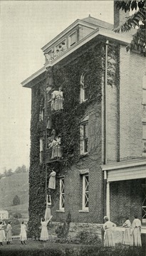 Scene of girls climbing down the side of a building as they practice a fire drill at the West Virginia Industrial Home for Girls.