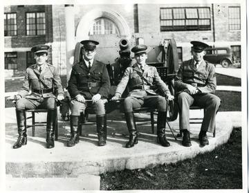 Group portrait of uniformed men with sabers drawn pose in front of Greenbrier Military School.