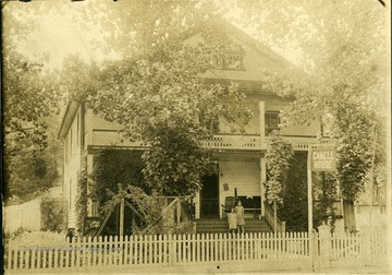 View of two girls standing on the steps of the Cabell House located on Main Street in White Sulphur Springs. 'The house was once used as a rooming house and small hotel. It was torn down in the late 1960s. Datsun automobile sales lot now on the site.'