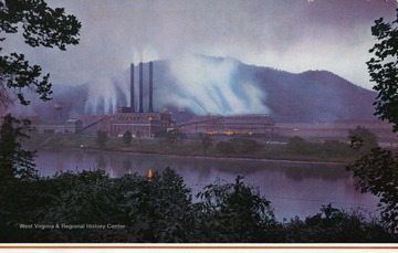 View of the Electro Metallurgical Company Plant at Alloy, W. Va. ' At Alloy, in the Kanawha River Valley in West Virginia, is located one of the ferro-alloy plants of Electro Metallurgical company. Here, ores from the far places of the earth are compounded and smelted in electric furnaces to produce ferro-alloys of chromium, manganese, silicon, vanadium, tungsten, and zirconium -- essential in making iron, steel, and other metals. One of the important products of this plant is low-carbon ferrochrome, which is used in the manufacture of stainless steel for thousands of uses in industry and in the home. A forerunner of the Alloy plant, farther up the river at Glen Ferris, started smelting ferrochrome as early as 1896. Several buildings of the metallurgical works at Alloy are pictured in the color photograph on the reverse. In the photograph can be seen the tall chimneys of the power plant and the brightly lighted windows furnace rooms.'