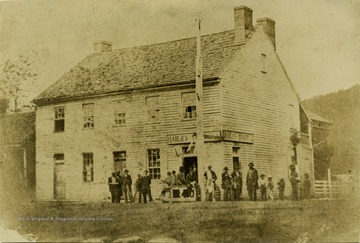 View of the old Bailey House, located on the corner of Main and Second Streets.  'The sign 'Bailey and Tunstil' on the store was Major Bailey and his son-in-law. In the group was David Bare, father; J. H. Bare, druggist; Andrew Edmiston, known as Sr., a long prominent lawyer; and John S. Camden, later of Parkersburg. Here Thomas Jackson, J. A. J. Lightburn, Johnson N. Camden, and G. J. Butcher took examination for West Point. Butcher won, stayed a week, then came home. Jackson went as a second choice.'