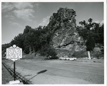 Two cars are parked in front of Pinnacle Rock near Bluefield in Mercer County, West Virginia. 'Pinnacle Rock: Erosion- Nature's cutting tool- has chiseled away the stone on this spur of Flat Top mountain, leaving this giant cockscomb more than 2700 feet above sea level. Several counties may be seen from these cliffs.'