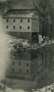 A view of the mill in the winter, with snow along the riverbanks.