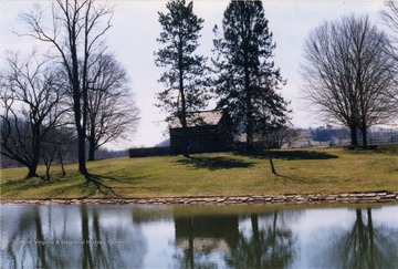 A view of a small building enclosed by a fence across the river at Jackson's Mill.