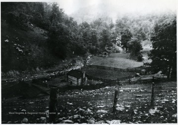 Small buildings sit next to a stream.