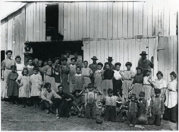 'This is the Eli Rice Canning Factory before 1908-Probably 1907.  I have original of this photo.  I will identify these people as they are identified on the back of an old print of it. The numbers are used to make row identification easier.  First Row, left to right: 1. Austin Newbraugh, 2. Henry Beeler, 3. Joe Miller, 4. Miller, 5. Dewey Rice, 6. Lacy Rice, 7. Miller, 8. Miller, 9. Mason.  Second Row: 10. unknown, 11. unknown, 12. Agnes Dawson, 13. Gladys Ziler, 14. Ziler, 15 Annie Ziler, 16. Fritzman, 17 Fritzman, 18. Ferry Ambrose, 19. unknown, 20 Lillie Miller, 21. Mae Ambrose, 22. Jessie Miller, 23. Miller, 24. Mrs. Eli Rice.  Third Row: 25. Clara Fearnow, 26 Mrs. Kelley Bohrer, 27. unknown, 28. Ruth Ziler, 29. Mrs. John Ziler, 30. unknown, 31. Fannie Newbraugh, 32. Mabel Hinckle, 33. unknown, 34 Edward Miller, 35. Eli Rice 'Owner of carrier', 36 John Ziler.  Back Row: 37. Robert Miller, 38. Chaffie Ziler, 39. Harry Bohrer.  It may be of interest to have further identification of some of these people. 1. Austin Newbraugh was my father. 5. Dewey Rice was assistant cashier of Old Morgan County Bank and later cashier of Citizens National Bank. 6. Lacy Rice was a lawyer, President of Old National Bank of Martinsburg and a one time regent of West Virginia University. 12. Agnes Dawson is still living in Berkeley Springs. 31. Fannie Hinckle is my mother. 32. Mabel Hinckel sister of my mother is mother of 2 prominent doctors - Jay Welch, deceased of Baylor University and Dr. Jack Welch, retired chief of staff at Hurtsler Clinic, Halsatead Kansas.  35. Eli Rice was a farmer, canner and bank director.  The Siler collection that you have some photos from was arranged by me through Lacey Rice as head of the bank settling the Siler Estate.  From Fred Newbraugh. 'Half hidden man with hat in back row - E. Rice.  Man in figured shirt with dog is Austin NewBraugh, his wife, Fanny Hinkel, is looking over shoulder in back row.'