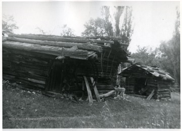 'Log Blacksmith Shop, roofed by clapboards with press poles - log outbuilding in background formerly a still.''