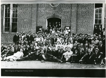 Group portrait of teachers standing outside brick building.