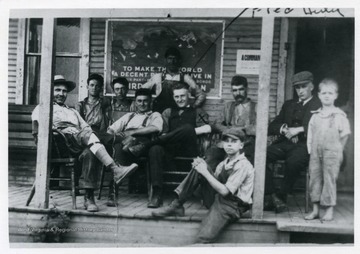 'Raine Andrews Lumber Company.  X marks Fred Hertig on the front porch of the Boarding House.  He is my brother. Note the poster on the wall, it is World War I.'