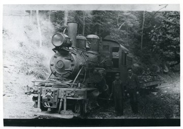 Two men standing to the right of a log engine. Albert Hertig of Evenwood, W. Va. standing on far right.