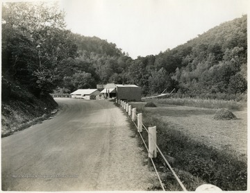 Gas Station along an unpaved road. 'Missouri Branch - Picture taken from Highway, U. S. Routh #52, looking west. Norfolk and Western Railroad in the distance beyond the far end of Highway Bridge over Twelve Pole Creek. Also, junction of County Road along Twelve Pole Creek with U. S. Route #52.'