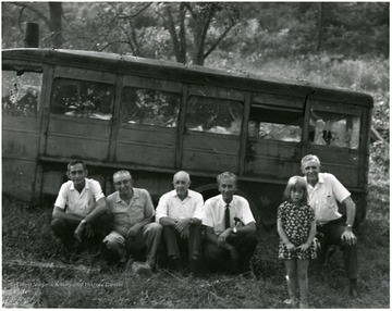 Five men and a young girl in front of the bus.