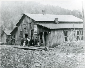View of people outside of a store in Wetzel County. Sign reads 'New process makes refined tobacco.  Best for smokers.'