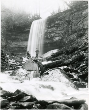 Two men standing in front of a water fall at Hills Creek Falls.