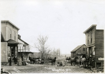 People with horses and buggies pose in Valley Point.  Hartman Hotel is on the left.