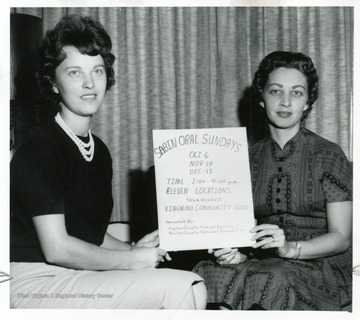 Two unidentified women with a sign that reads; "Sabin Oral Sundays, Oct. 6th, Nov. 10th, Dec. 15th.  Time:2:00-4:00p.m.  Eleven locations, your nearest community building.  Sponsored by; Preston County Medical Society and Preston County National Foundation."