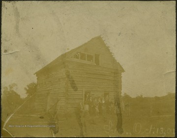 'Pictured is where George Washington stayed in a log cabin for a night and a day in Monongalia County. Pictured standing on the front steps are George Willard, John Ware, Alex Fields, Walter Brewer, Leo Willard, Ida Hinkel, Birdie Layman, Mattie Mathews, and Leannie Mathews.'