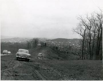 Car pulled to the side of the road near where trees are being cut.  Morgantown and Westover homes visible in the distance.