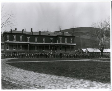 Members of the West Virginia University Military Unit are standing at attention in front of the West Virginia Agricultural Experiment Station. 