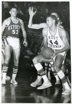 'West Virginia's Mr. Everything, Jerry West (44) slips by a Virginia Military (Institute) defender on his way to scoring one of the 12 field goals he scored 12/14. West was outscored by VMI's Joe Gedro (53) who tallied 30. WVU won, 91-76. UPI Telephoto.'
