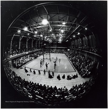 'A crowd of 6,200 viewed the final game in historic Mountaineer Field House as the cagers finished an illustrious history with a record of 374-77 since 1929.  In the picture are Bob Hummell (shooting free throw), Wil Robinson (center circle), Larry Woods (32), Dick Symons (45) and Mike Heitz (opposite Woods) of West Virginia; Bill Downes (35), Mike Paul (next to Downes), Phil Bushkar (under basket)and Bill Brill.'