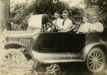 In the driver's seat is Warren Cunningham, beside him is Bradford Cunningham, and in the backseat is Oather Cunningham and Homer Lovejoy.