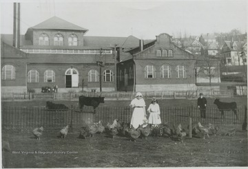 'I. C. White, wife and daughter on White property, site of present Chemistry Building Annex.  The entire White property now is the site of the Mineral Industry (White Hall) Building, Library, Chemistry Building, and Annex.  In front of Mechanical Hall, Prospect Street where library is now.'
