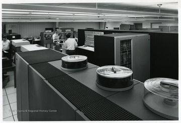 Three men working on machines at the computer center in Evansdale Campus.