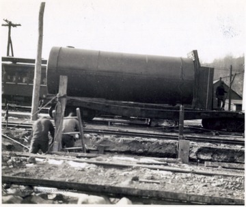 A large tank or pipe has been transported by rail car to the site.