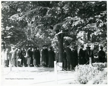 'Commencement participants standing in front of E. Moore Hall'.