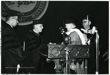 President Paul Miller granting a degree, left; Stan Harris on right.