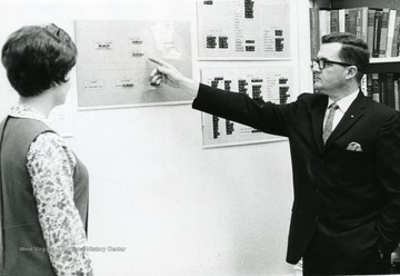 James Watkins pointing to an organization chart for female colleague.